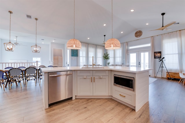 kitchen with lofted ceiling, an island with sink, sink, white cabinetry, and appliances with stainless steel finishes