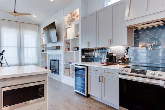 kitchen featuring light hardwood / wood-style flooring, stainless steel appliances, beverage cooler, a fireplace, and tasteful backsplash