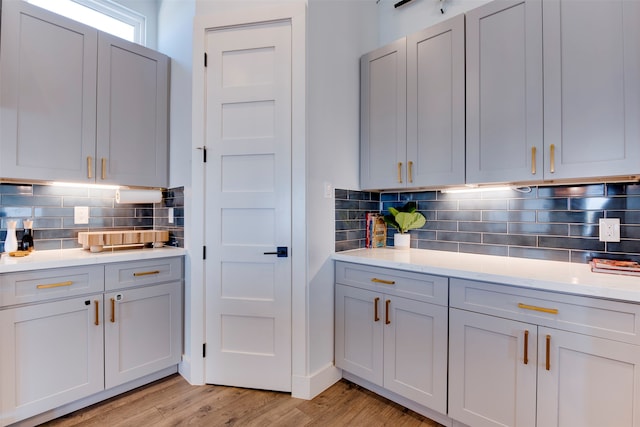 kitchen with decorative backsplash, light stone counters, and light wood-type flooring