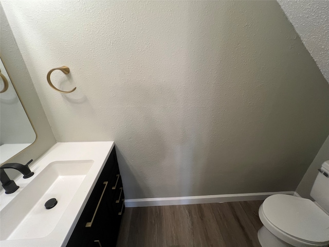 bathroom featuring toilet, vanity, and hardwood / wood-style flooring