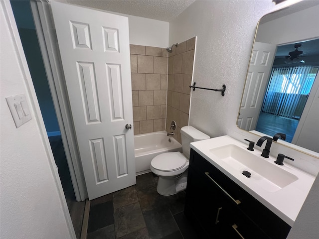 full bathroom with vanity, a textured ceiling, tiled shower / bath combo, ceiling fan, and toilet