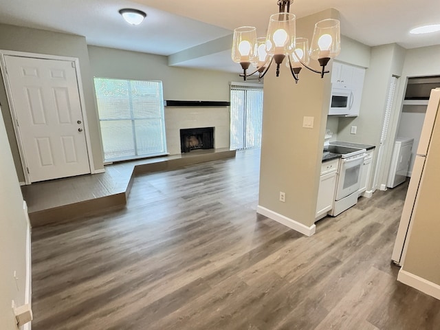 kitchen featuring white appliances, a notable chandelier, hardwood / wood-style floors, white cabinetry, and hanging light fixtures