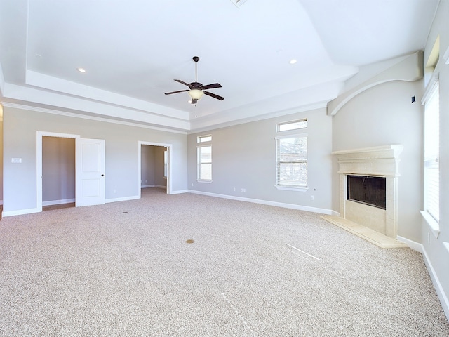 unfurnished living room featuring carpet floors, a tray ceiling, and ceiling fan