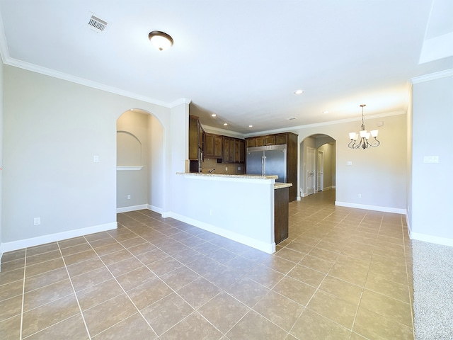 kitchen with light stone counters, crown molding, an inviting chandelier, and built in refrigerator