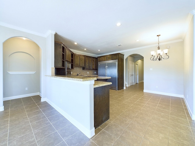 kitchen with dark brown cabinets, stainless steel built in refrigerator, tasteful backsplash, and hanging light fixtures