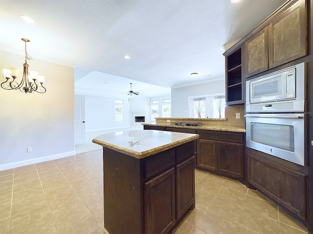 kitchen with ornamental molding, light tile patterned flooring, light stone counters, and stainless steel appliances