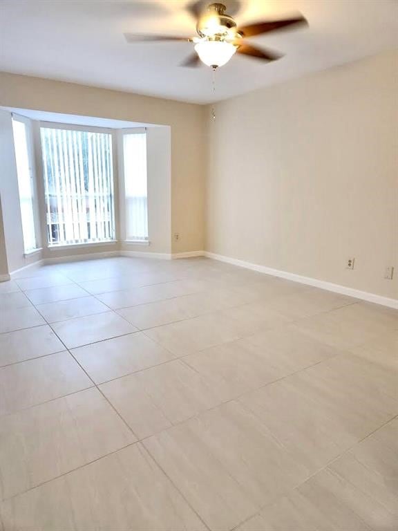 tiled spare room featuring ceiling fan