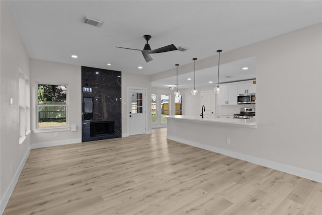 unfurnished living room with a fireplace, light hardwood / wood-style flooring, and ceiling fan