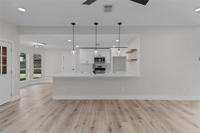 kitchen with white cabinets, light hardwood / wood-style floors, decorative light fixtures, and appliances with stainless steel finishes