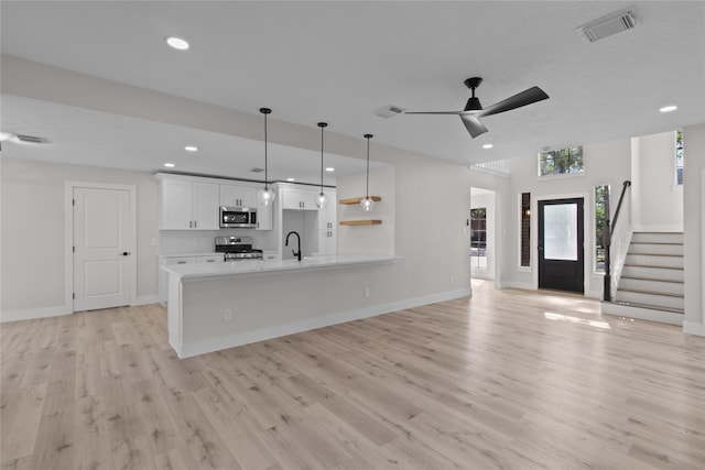 kitchen featuring ceiling fan, hanging light fixtures, stainless steel appliances, white cabinets, and light wood-type flooring