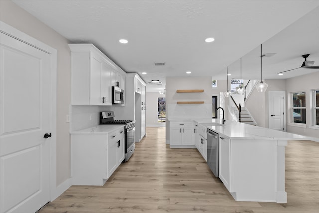 kitchen with white cabinets, decorative light fixtures, sink, and appliances with stainless steel finishes