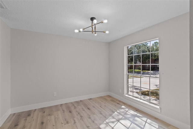 unfurnished room featuring light wood-type flooring and a notable chandelier