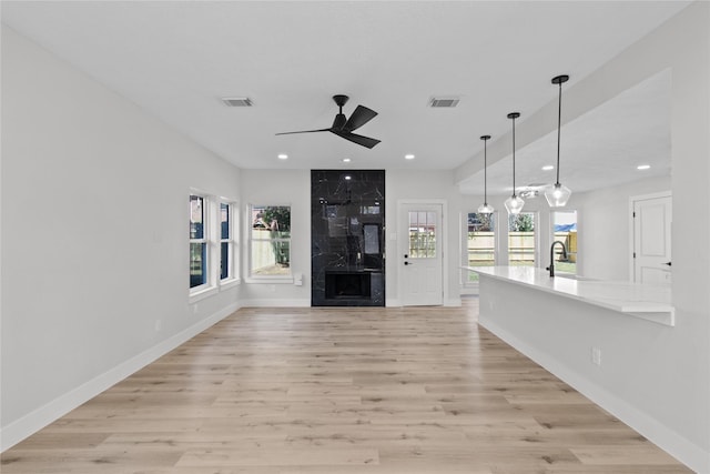 unfurnished living room featuring ceiling fan, light wood-type flooring, and sink