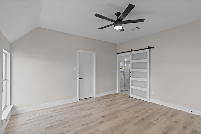 unfurnished bedroom with a barn door, light hardwood / wood-style flooring, ceiling fan, and lofted ceiling