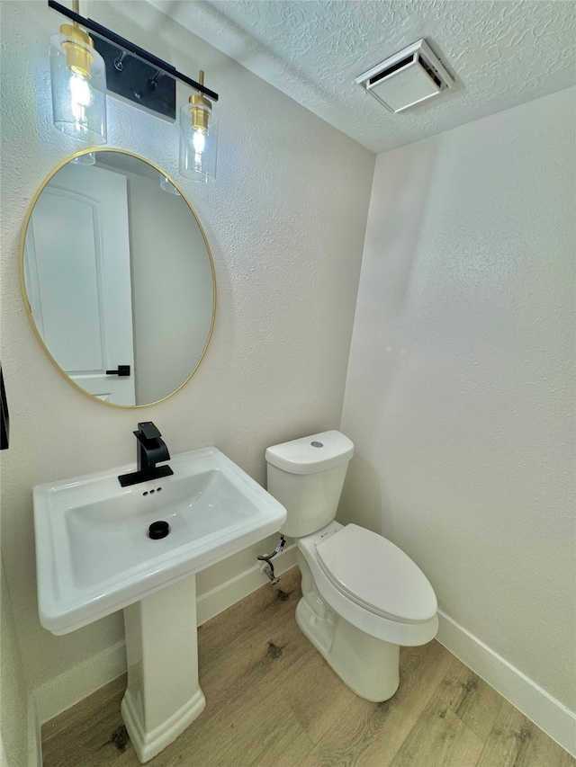 bathroom featuring hardwood / wood-style floors, toilet, and a textured ceiling