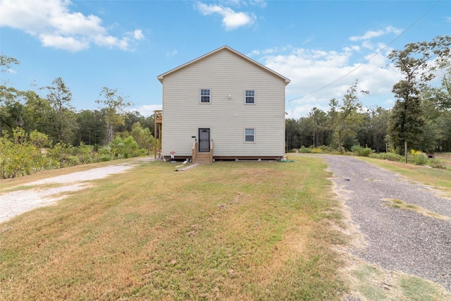 back of house featuring driveway and a lawn