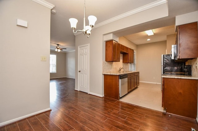 kitchen featuring decorative backsplash, dark hardwood / wood-style floors, crown molding, decorative light fixtures, and appliances with stainless steel finishes