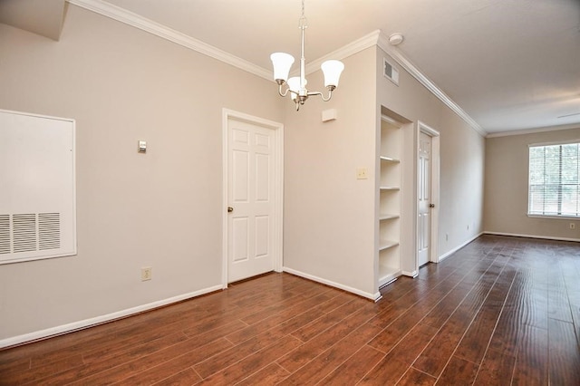 spare room featuring ornamental molding, dark hardwood / wood-style floors, and a chandelier