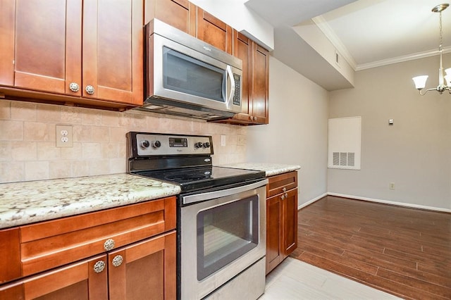 kitchen featuring hanging light fixtures, crown molding, a notable chandelier, appliances with stainless steel finishes, and light hardwood / wood-style floors