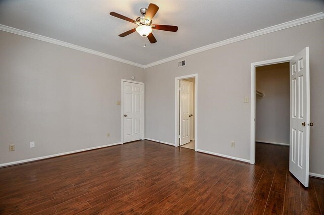 unfurnished bedroom featuring ornamental molding, dark hardwood / wood-style floors, a spacious closet, and ceiling fan