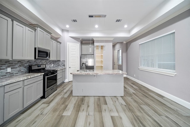 kitchen with pendant lighting, gray cabinets, appliances with stainless steel finishes, and light hardwood / wood-style floors