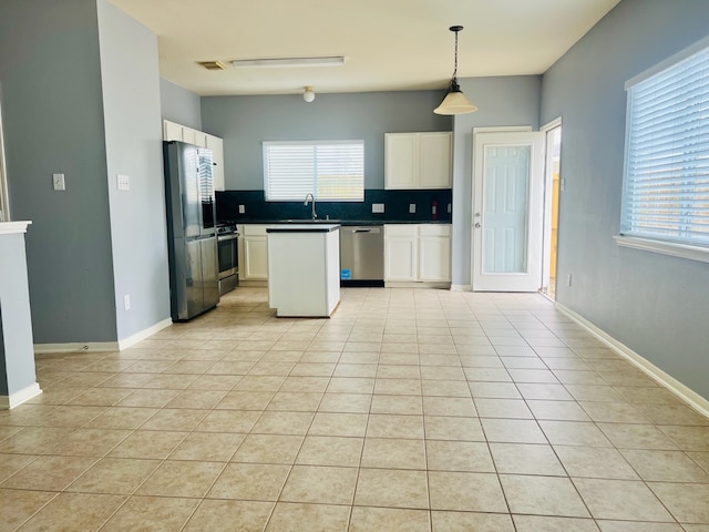 kitchen featuring plenty of natural light, hanging light fixtures, stainless steel appliances, and white cabinets