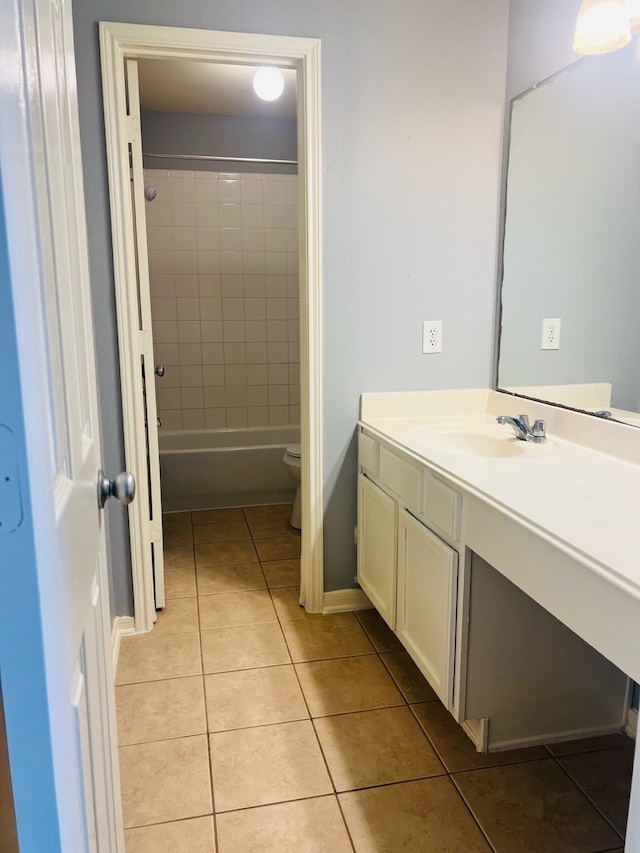 full bathroom featuring tiled shower / bath, vanity, toilet, and tile patterned floors