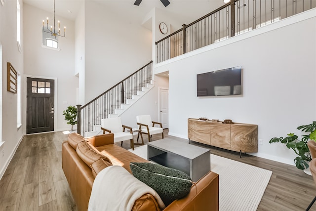 living room with hardwood / wood-style flooring, a towering ceiling, and ceiling fan with notable chandelier