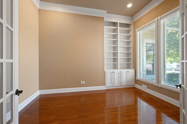 spare room with built in features, crown molding, and baseboards