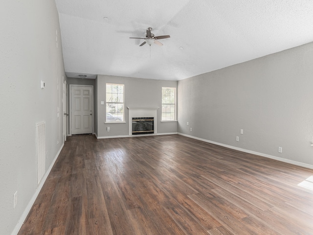 unfurnished living room featuring a textured ceiling, dark hardwood / wood-style flooring, and ceiling fan