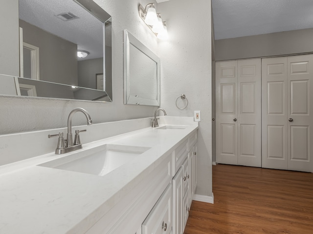 bathroom with vanity, a textured ceiling, and hardwood / wood-style flooring