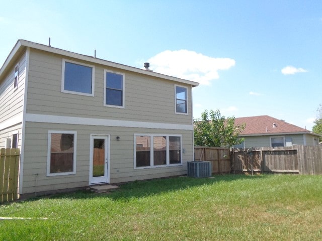 back of property featuring cooling unit and a yard