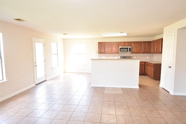 kitchen with backsplash, light tile patterned floors, and a center island