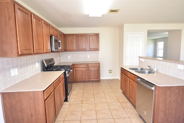 kitchen with decorative backsplash, stainless steel appliances, sink, and light tile patterned floors