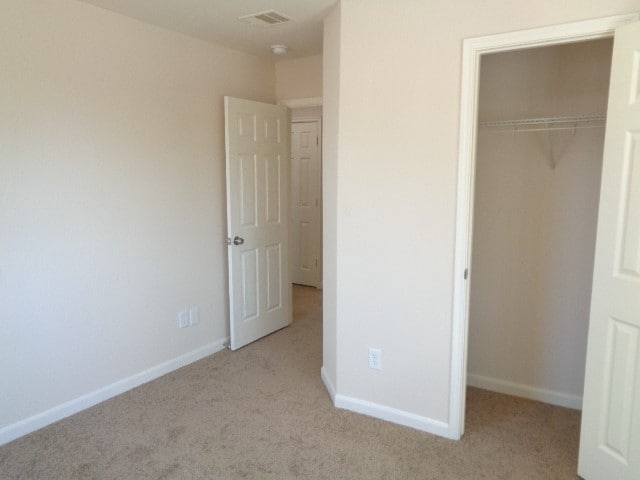 unfurnished bedroom with light colored carpet and a closet