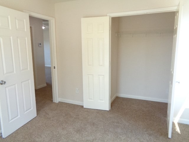 unfurnished bedroom with light carpet and a closet