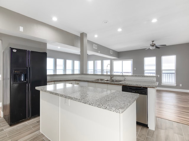 kitchen with sink, a kitchen island, black refrigerator with ice dispenser, light hardwood / wood-style floors, and stainless steel dishwasher