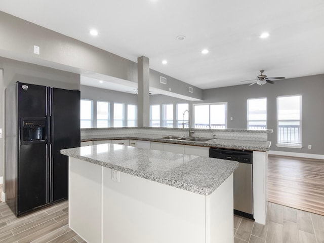 kitchen featuring black refrigerator with ice dispenser, stainless steel dishwasher, a sink, ceiling fan, and wood finish floors