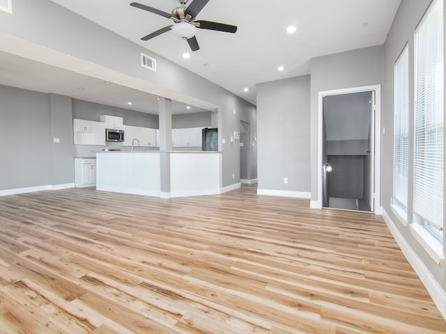 unfurnished living room with sink, light hardwood / wood-style flooring, and ceiling fan