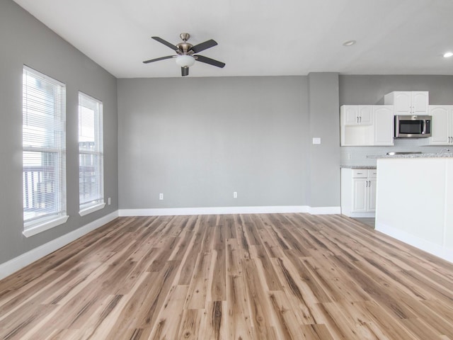 unfurnished living room featuring baseboards, a ceiling fan, and light wood-type flooring
