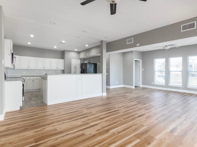 unfurnished living room with light wood finished floors, a ceiling fan, and visible vents