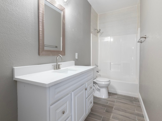 full bathroom featuring wood finished floors, a textured wall, shower / bath combination, toilet, and vanity