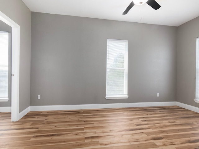 unfurnished room featuring baseboards, a ceiling fan, light wood finished floors, and a healthy amount of sunlight