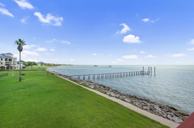 view of dock with a lawn and a water view