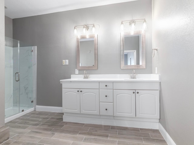 bathroom featuring wood finish floors, baseboards, a marble finish shower, and a sink