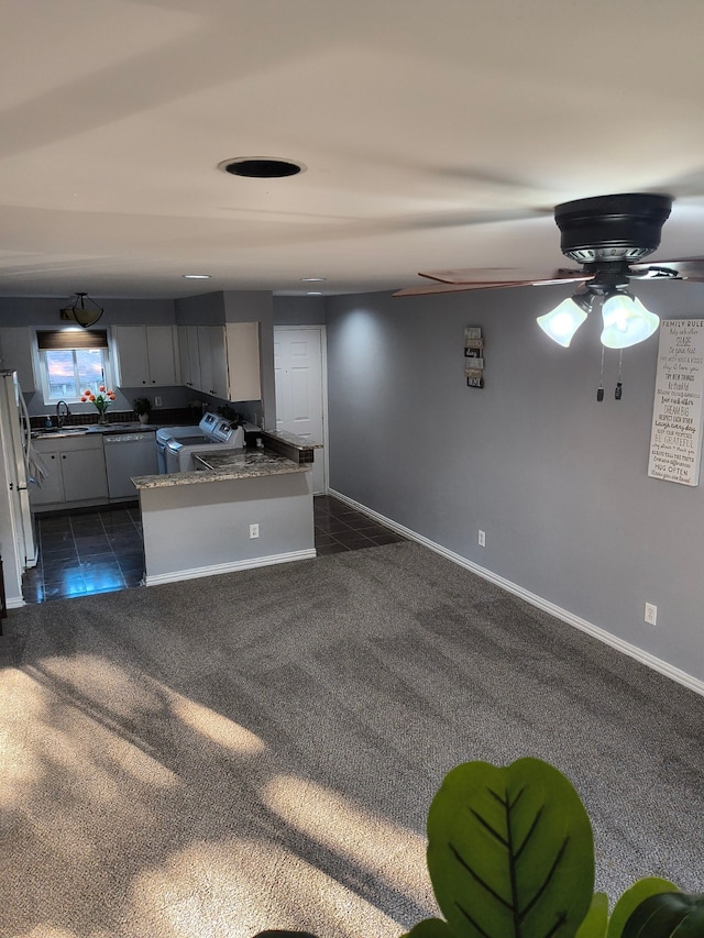 kitchen featuring white appliances, kitchen peninsula, and dark carpet