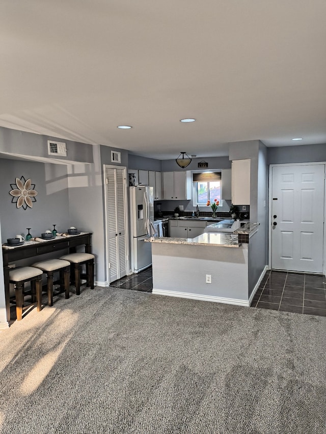 12100 Melville Dr Unit 406D, Montgomery, TX 77356 - kitchen with stainless steel fridge with ice dispenser, baseboards, a peninsula, white cabinets, and dark carpet