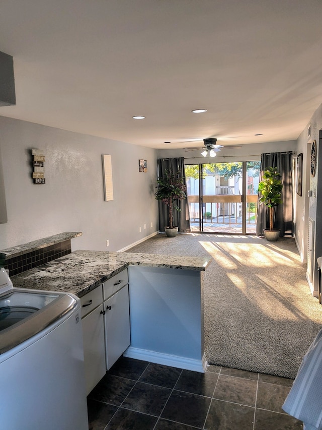 kitchen featuring dark carpet, white cabinets, light stone counters, ceiling fan, and washer / clothes dryer