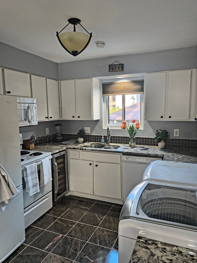 kitchen featuring white cabinets, wine cooler, sink, white appliances, and dark stone countertops