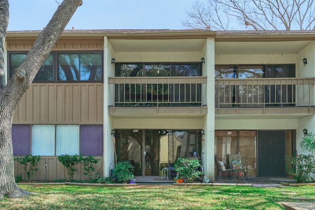 rear view of property with a balcony and a lawn